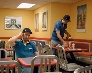 Employee Randy Leyner (left) sits while Ehrman clears a table.